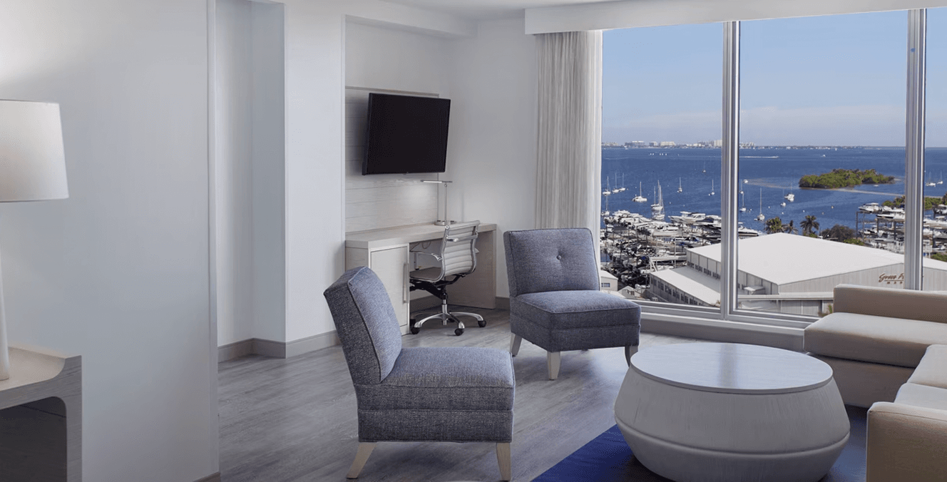 Furnished guest room at Marriott Courtyard Miami with a bed, lounge chair and window overlooking greenery