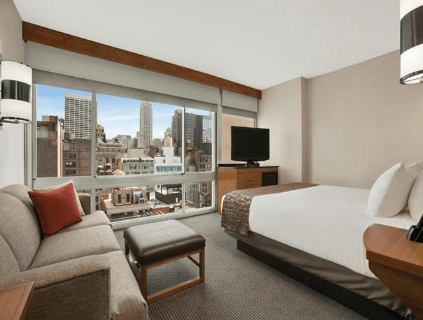 Furnished hotel guest room interior with layered lighting and a seating area